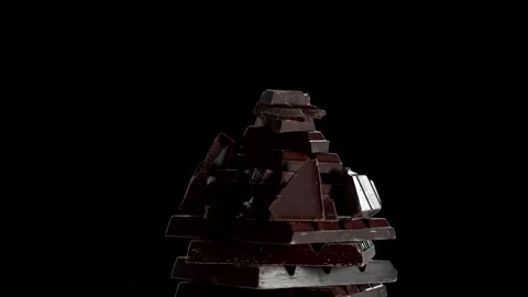 A stack of dark chocolate pieces rotating against dark background. Stock Footage 237597056