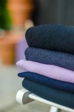 Stack of dark coloured sweater on white wood chair Stock Photos