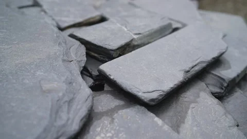 Stack of dark gray natural slate roofing tiles showing rough textured Stock Footage 345846077