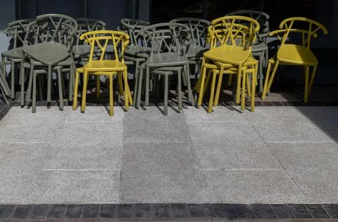 Stack of Dark green (Khaki color) and Yellow plastic chairs are beside of T.. Stock Photos