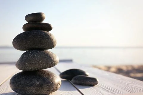 Stack of dark stones on wooden deck near sea. Zen concept Foto stock
