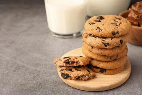 Stack of delicious chocolate chip cookies and milk on grey table. Space for.. Stock Photos