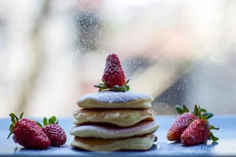 Stack of delicious fluffy pancakes with fresh strawberries and sugar and hone Stock Photos