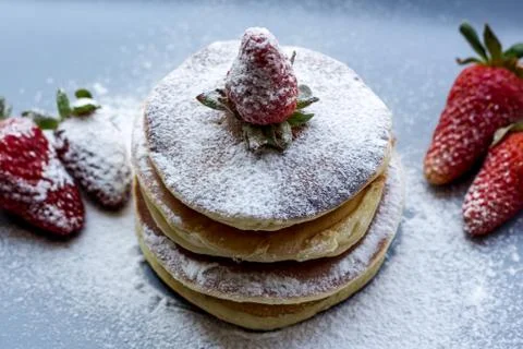Stack of delicious fluffy pancakes with fresh strawberries and sugar and hone Stock Photos