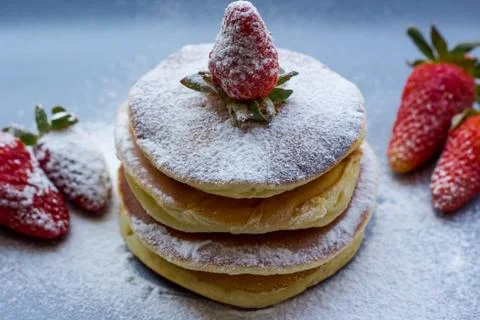 Stack of delicious fluffy pancakes with fresh strawberries and sugar and hone Stock Photos
