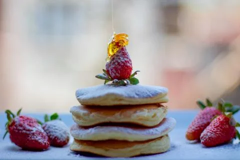 Stack of delicious fluffy pancakes with fresh strawberries and sugar and hone Stock Photos