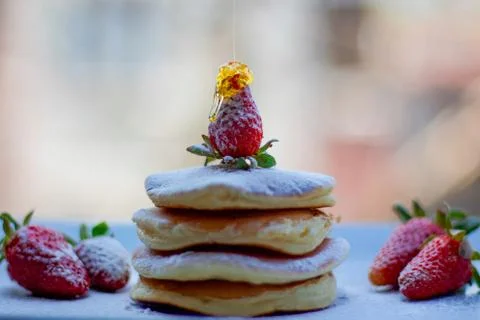 Stack of delicious fluffy pancakes with fresh strawberries and sugar and hone Stock Photos