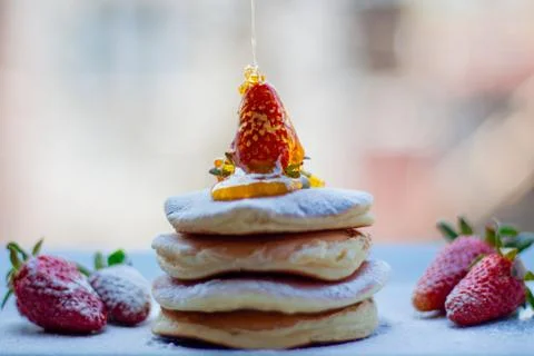 Stack of delicious fluffy pancakes with fresh strawberries and sugar and hone Stock Photos