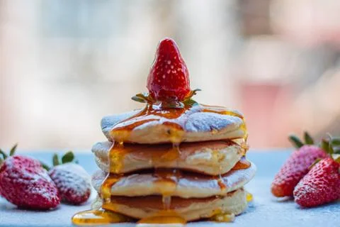 Stack of delicious fluffy pancakes with fresh strawberries and sugar and hone Stock Photos