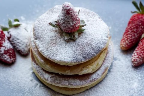 Stack of delicious fluffy pancakes with fresh strawberries and sugar and hone Stock Photos