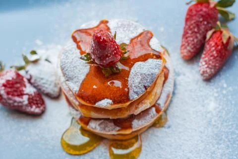Stack of delicious fluffy pancakes with fresh strawberries and sugar and hone Stock Photos
