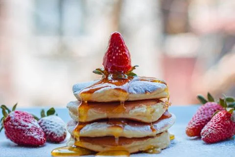 Stack of delicious fluffy pancakes with fresh strawberries and sugar and hone Stock Photos