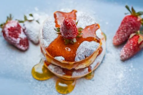 Stack of delicious fluffy pancakes with fresh strawberries and sugar and hone Stock Photos