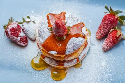 Stack of delicious fluffy pancakes with fresh strawberries and sugar and hone Stock Photos