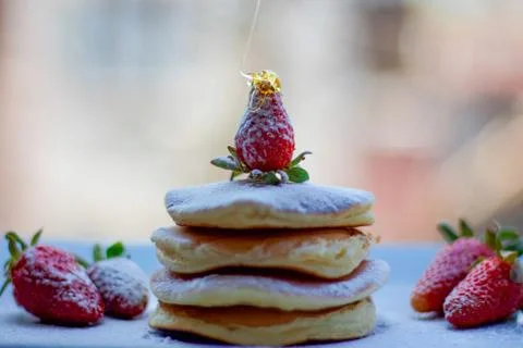 Stack of delicious fluffy pancakes with fresh strawberries and sugar and hone Stock Photos