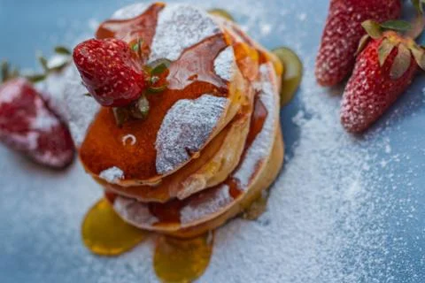 Stack of delicious fluffy pancakes with fresh strawberries and sugar and hone Stock Photos