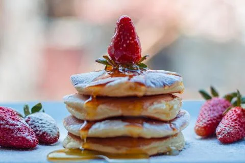 Stack of delicious fluffy pancakes with fresh strawberries and sugar and hone Stock Photos