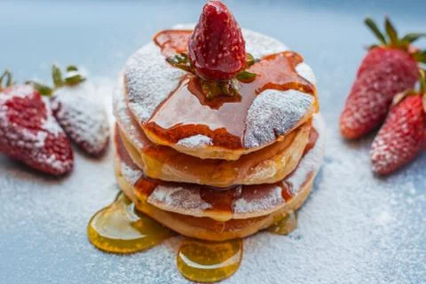 Stack of delicious fluffy pancakes with fresh strawberries and sugar and hone Stock Photos