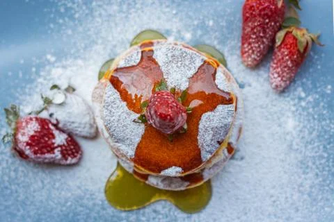 Stack of delicious fluffy pancakes with fresh strawberries and sugar and hone Stock Photos
