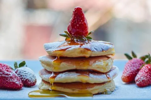 Stack of delicious fluffy pancakes with fresh strawberries and sugar and hone Stock Photos