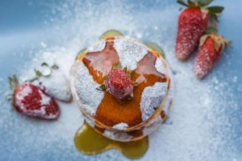Stack of delicious fluffy pancakes with fresh strawberries and sugar and hone Stock Photos