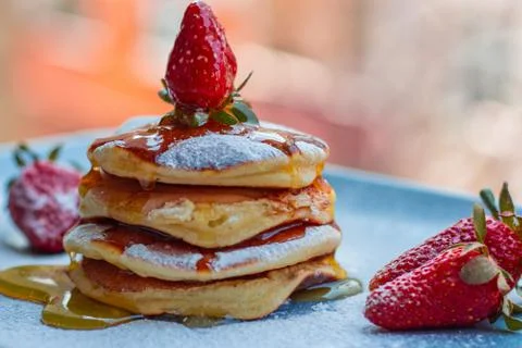 Stack of delicious fluffy pancakes with fresh strawberries and sugar and hone Stock Photos