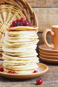 Stack of delicious pancakes with cranberries on plate and napkin wooden backg Stock Photos