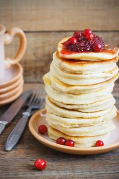 Stack of delicious pancakes with cranberries on plate and napkin wooden backg Stock Photos