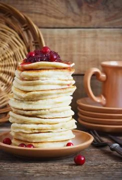 Stack of delicious pancakes with cranberries on plate and napkin wooden backg Stock Photos