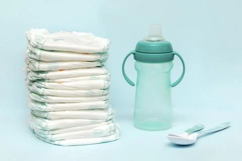 Stack of diapers, bottle milk, pacifier, spoons on table. set for infant ne.. Stock Photos