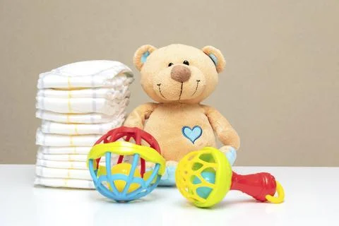 Stack of diapers, cute teddy bear with toys on table. set for boy girl for .. Stock Photos