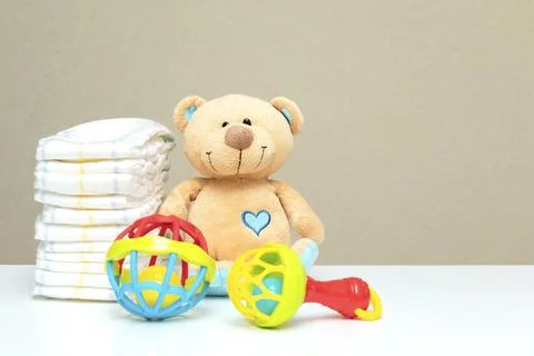 Stack of diapers, cute teddy bear with toys on table. set for boy, girl, fo.. Stock Photos