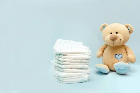 Stack of diapers with cute teddy bear toy on table. set for infant newborn .. Stock Photos