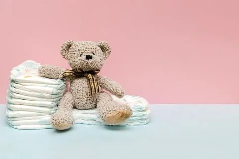 Stack of diapers with cute teddy bear toy on table. set for newborn infant .. Stock Photos