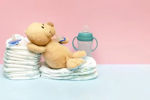 Stack of diapers with cute teddy bear toy pacifier lying on table. set for .. Stock Photos