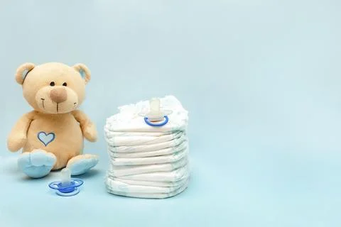 Stack of diapers with cute teddy bear toy on table. set for infant newborn .. Stock Photos