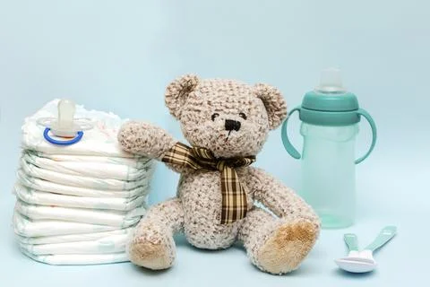 Stack of diapers with cute teddy bear toy, bottle of milk on table. set for.. Stock-Fotos