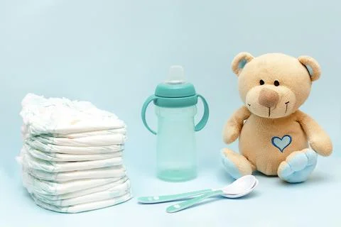 Stack of diapers with cute teddy bear toy, bottle of milk on table. set for i Stock-Fotos