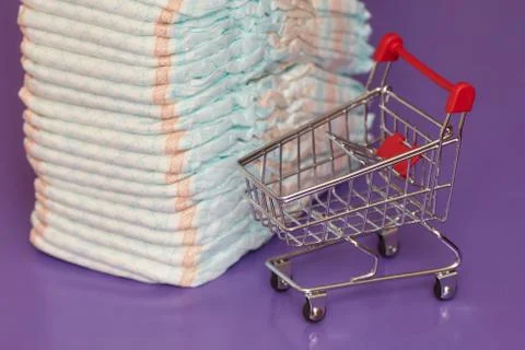 Stack of diapers or nappies and mini shopping cart, concept Foto stock