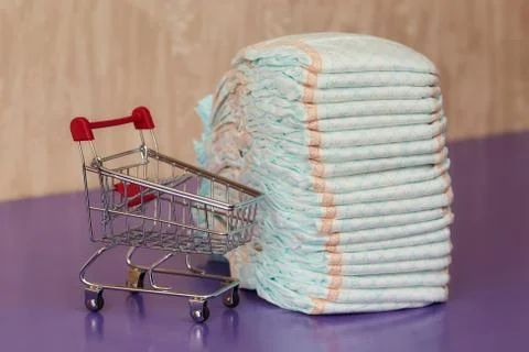 Stack of diapers or nappies and mini shopping cart, concept Foto stock
