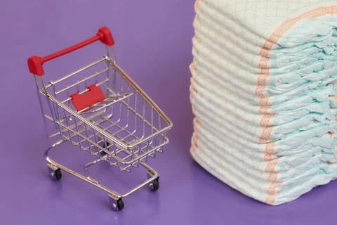 Stack of diapers or nappies and mini shopping cart, concept Stock Photos