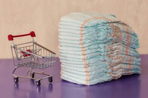Stack of diapers or nappies and mini shopping cart, concept Stock Photos