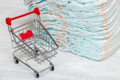 Stack of diapers or nappies and mini shopping cart, concept Stock Photos