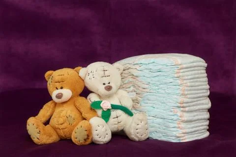 Stack of diapers or nappies with teddy bears, purple background Foto stock