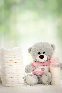 Stack of diapers with soft teddy bear on table Stock Photos