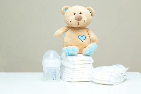 Stack of diapers with toy teddy bear and bottle of milk. set for boy girl f.. Stock Photos