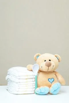Stack of diapers with toy teddy bear with spoon on table. set for baby show.. Foto stock