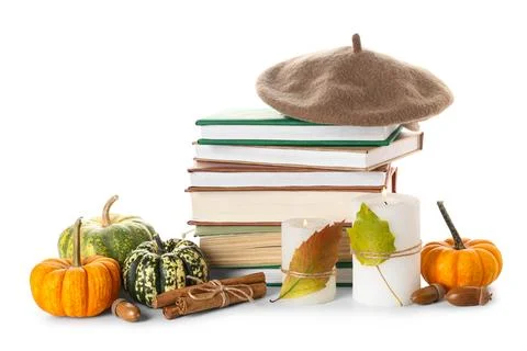 Stack of different books with beret hat, burning candles, cinnamon sticks, pu Stock Photos