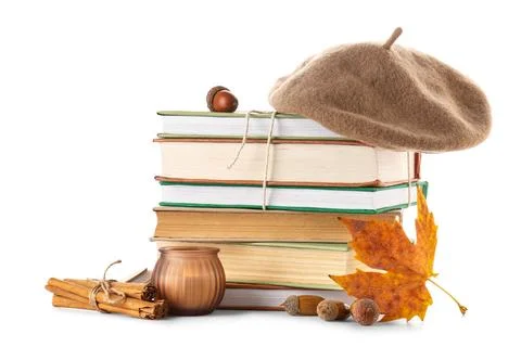 Stack of different books with beret hat, burning candle, cinnamon sticks, aco Stock Photos