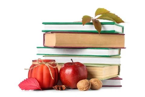 Stack of different books with burning candle, apple, walnuts and autumn leave Stock Photos